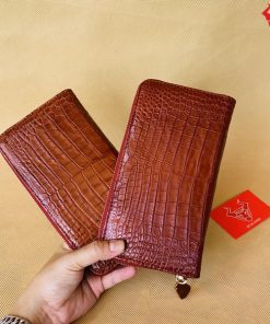 Mặt Trước Ví Cầm Tay: Chiếc ví cầm tay được làm từ da cá sấu màu nâu đỏ tự nhiên, mang đến vẻ đẹp sang trọng và độc đáo. Thiết kế da bụng nổi bật tạo điểm nhấn thu hút sự chú ý.
