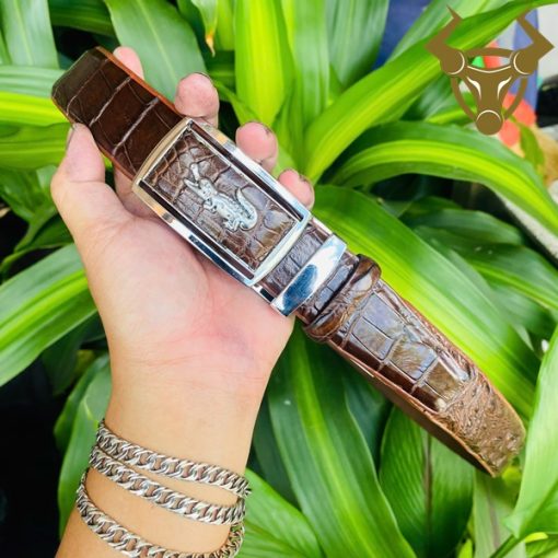 Mặt khóa trắng vàng sang trọng trên nền da cá sấu nâu đậm.