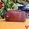 Một chiếc túi clutch hộp da cá sấu màu nâu đất, thể hiện phong cách thời trang cao cấp và đẳng cấp cổ điển.