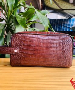 Một chiếc túi clutch hộp da cá sấu màu nâu đất, thể hiện phong cách thời trang cao cấp và đẳng cấp cổ điển.