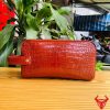 Một chiếc túi clutch da cá sấu đỏ, thể hiện phong cách thời trang sang trọng và gọn gàng.