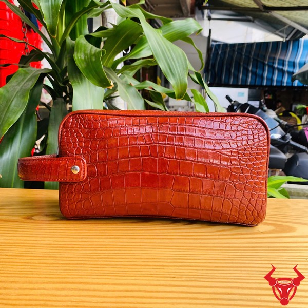 Thời trang nổi bật với clutch da cá sấu đỏ Một chiếc túi clutch da cá sấu đỏ, thể hiện phong cách thời trang sang trọng và gọn gàng.