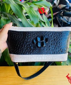 Hình ảnh túi đeo chéo da cá sấu gù HM-17 màu đen trắng, đặt trên bàn gỗ, thể hiện phong cách sang trọng và thời thượng.