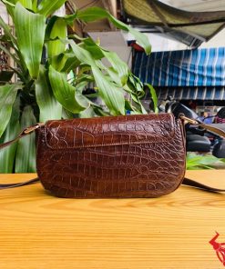Hình ảnh túi đeo vai da cá sấu HM-20 màu nâu, đặt trên bàn gỗ, nổi bật với phong cách sang trọng.