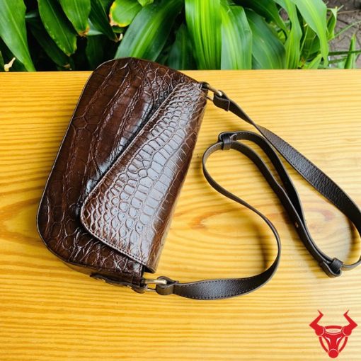 Hình ảnh túi đeo vai da cá sấu HM-20 màu nâu, đặt trên bàn gỗ, thể hiện phong cách sang trọng và cá tính.