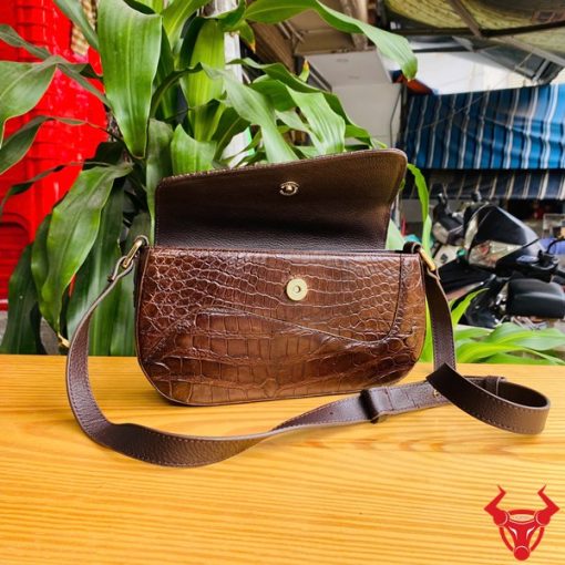 Hình ảnh túi đeo vai da cá sấu HM-20 màu nâu, đặt trên bàn gỗ, nổi bật với phong cách thời trang sang trọng.
