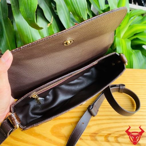 Hình ảnh túi đeo vai da cá sấu HM-20 màu nâu, đặt trên bàn gỗ, thể hiện phong cách thời trang sang trọng và cá tính.