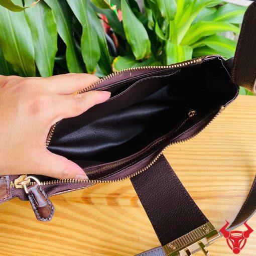 Hình ảnh túi đeo vai da bụng cá sấu HM-19 màu nâu, khóa vàng, đặt trên giá gỗ, nổi bật với phong cách thời trang sang trọng.