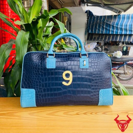 Túi xách du lịch da cá sấu phối xanh navy và xanh dương nổi bật, tay cầm chắc chắn.