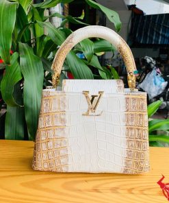 Hình ảnh túi xách da cá sấu bạch tạng nhũ vàng, đặt trên bàn gỗ, thể hiện sự sang trọng và quý phái.