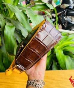 Hình ảnh túi xách da bụng cá sấu HM-18, nâu vàng viền da bò, đặt trên giá gỗ, thể hiện phong cách sang trọng.