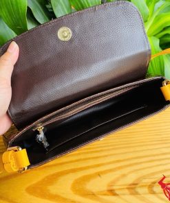 Hình ảnh túi xách da bụng cá sấu HM-18, nâu vàng viền da bò, đặt trên giá gỗ, nổi bật với phong cách thời trang sang trọng.