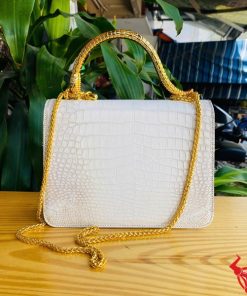 Hình ảnh túi xách da cá sấu bạch tạng HM-16, quai vàng rắn, đặt trên bàn gỗ, nổi bật với phong cách thời thượng.