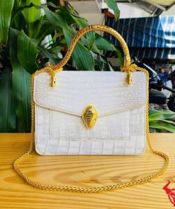 Hình ảnh túi xách da cá sấu bạch tạng HM-16, quai vàng rắn, đặt trên bàn gỗ, thể hiện đẳng cấp và cá tính.