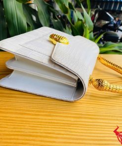 Hình ảnh túi xách da cá sấu bạch tạng HM-16, quai vàng rắn, đặt trên bàn gỗ, thể hiện phong cách quý phái và cá tính.