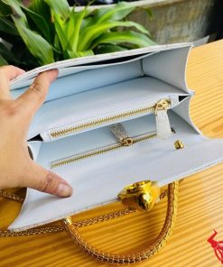 Hình ảnh túi xách da cá sấu bạch tạng HM-16, quai vàng rắn, đặt trên bàn gỗ, thể hiện sự sang trọng và cá tính.