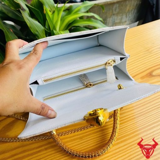 Hình ảnh túi xách da cá sấu bạch tạng HM-16, quai vàng rắn, đặt trên bàn gỗ, thể hiện sự sang trọng và cá tính.