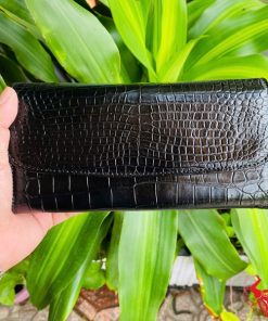 Ví nữ da cá sấu ba gấp màu đen sang trọng cầm trên tay.