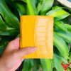 Một chiếc ví da bụng cá sấu màu vàng nổi bật, thiết kế thời trang, thể hiện đẳng cấp và phong cách cao cấp.