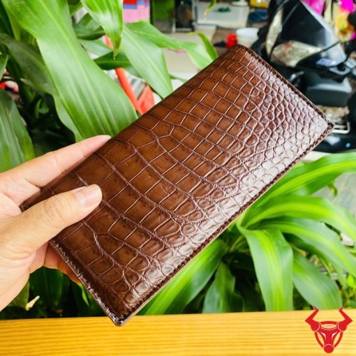 Cận cảnh ví cầm tay nâu đất bằng da cá sấu thật, bề mặt vân đẹp.