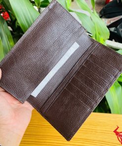 Tay nam giới cầm ví da bụng cá sấu bóng nâu sang trọng.