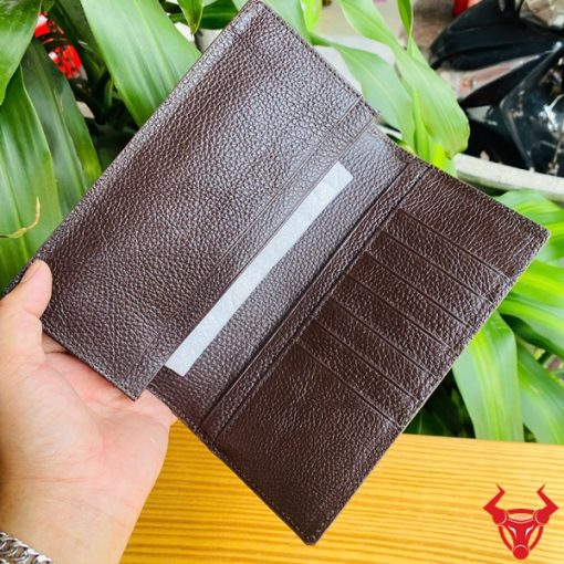 Tay nam giới cầm ví da bụng cá sấu bóng nâu sang trọng.