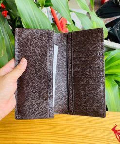 Hình ảnh tay người cầm ví cầm tay nâu bóng da bụng cá sấu thật.