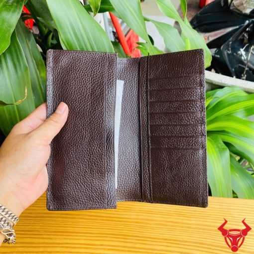 Hình ảnh tay người cầm ví cầm tay nâu bóng da bụng cá sấu thật.
