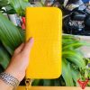 Ví da cá sấu bụng màu vàng sang trọng được cầm trên tay.
