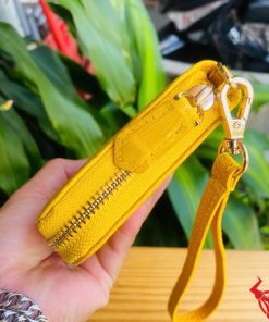 Ví cầm tay màu vàng, da bóng nhẹ, chế tác từ da cá sấu thật.