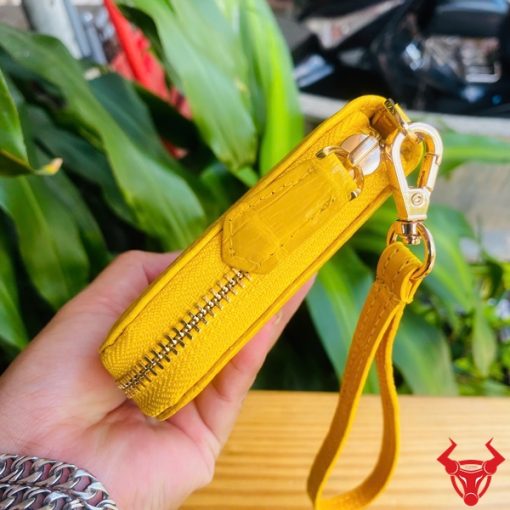 Ví cầm tay màu vàng, da bóng nhẹ, chế tác từ da cá sấu thật.