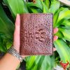 Một chiếc ví da cá sấu nguyên con màu nâu đỏ đậm sang trọng, thiết kế thời trang, thể hiện đẳng cấp và phong cách cao cấp.