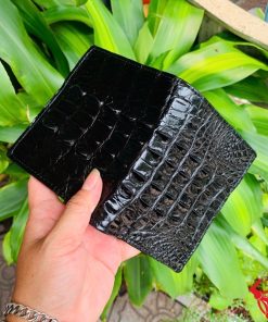 Cận cảnh ví da cá sấu đen gai lưng sắc nét trên tay nam giới.