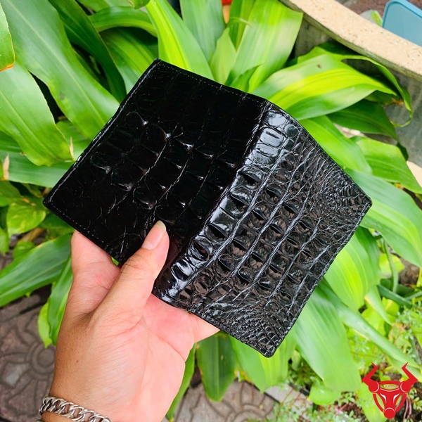 Cận cảnh ví da cá sấu đen gai lưng sắc nét trên tay nam giới.