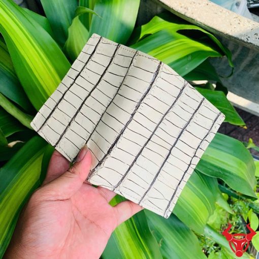 Ví da cá sấu trắng với đường vân đen, cầm trên tay người đeo vòng bạc.