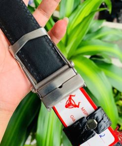 Hình ảnh thắt lưng TSK32 màu đen, da cá sấu sang trọng, mặt khóa lăn inox, cầm trên tay với nền cây xanh.