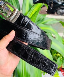 Hình ảnh thắt lưng TSK73 màu đen, da cá sấu cao cấp, mặt khóa ray trượt inox, cầm trên tay trước nền cây xanh.