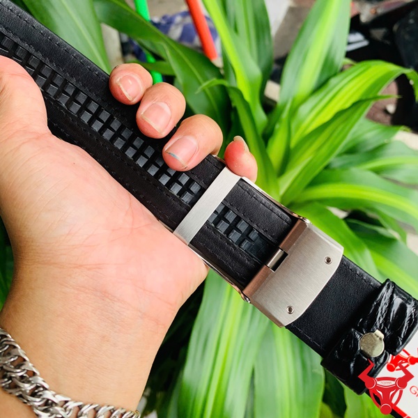 Thắt Lưng Sang Trọng Da Cá Sấu TSK73 Hình ảnh thắt lưng TSK73 màu đen, da cá sấu sang trọng, mặt khóa ray trượt inox, cầm trên tay với cây xanh phía sau.