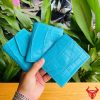 Hình ảnh ba chiếc ví nữ 3 gấp mini da bụng cá sấu VRAA8 màu xanh dương được cầm trên tay, nền xanh lá cây, thể hiện sự thời trang, phong cách và nhỏ gọn.