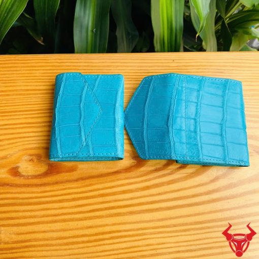 Hình cầm ba ví mini da cá sấu VRAA8 3 gấp màu xanh, nền xanh tươi, thể hiện thời trang, phong cách nhỏ gọn cho phụ nữ.